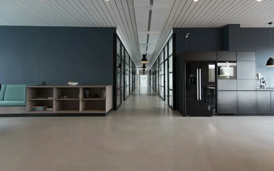 Long couloir d'un bureau moderne aux murs bleu-gris et aux cloisons vitrées