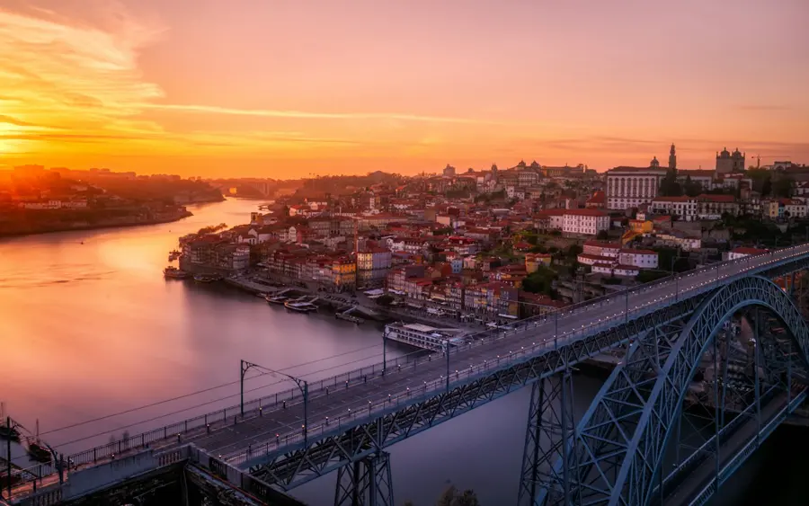 Pont métallique au-dessus du fleuve et quartier de Porto au coucher du soleil